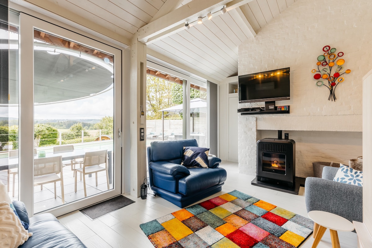 Salon du Gîte de Lierneux avec poêle à pellets et vue sur la terrasse et le jardin